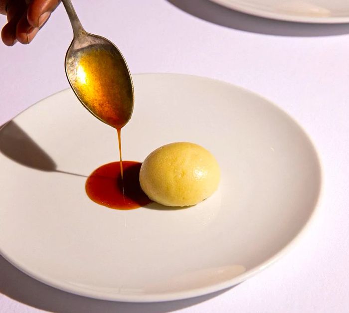 A chef pours sauce alongside a ball of uJeqe noMsobho.