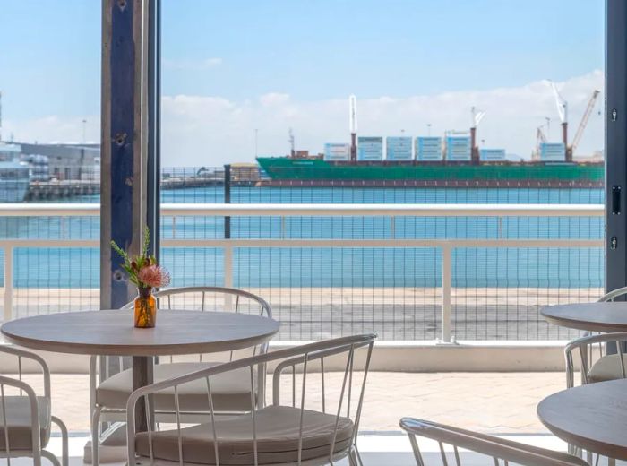 Restaurant tables with a stunning view of the harbor through large, bright windows.