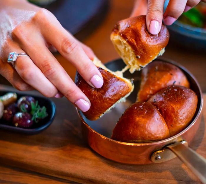 Hands separate rolls from a baking pan.