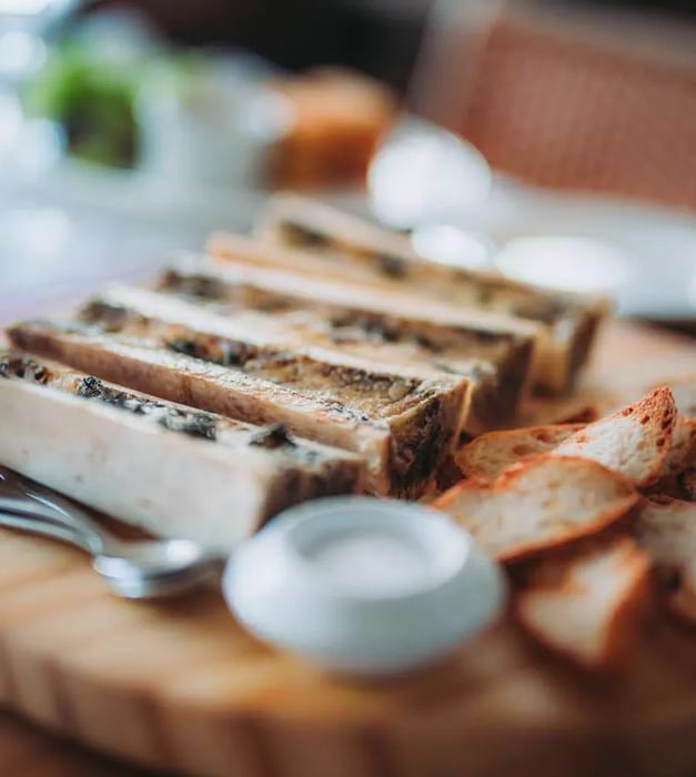 Bone marrow presented on a serving board alongside bread.