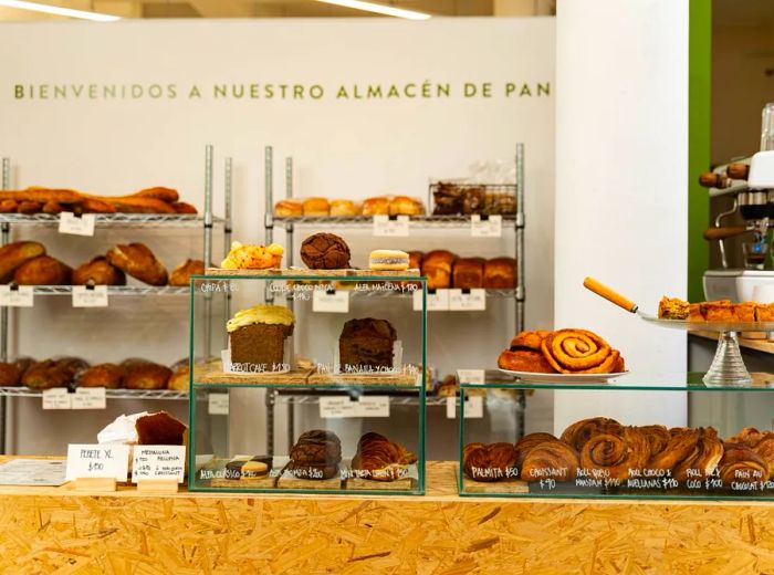 An array of pastries and loaves displayed behind a bakery counter.