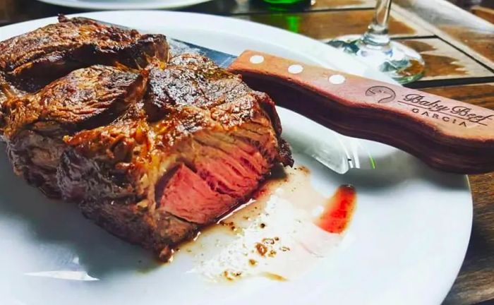 A close-up of a juicy steak sliced to showcase its red center, accompanied by a branded steak knife.