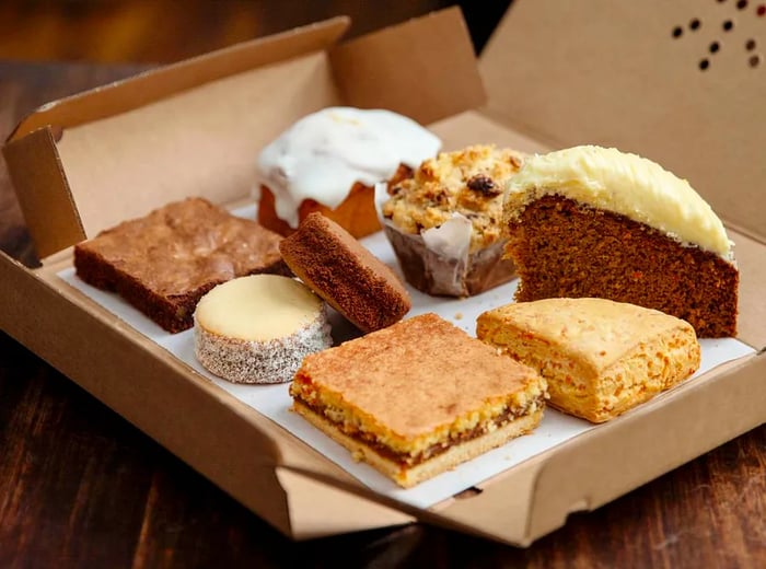 An open cardboard box showcasing an assortment of pastries and sweets.