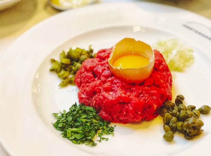 A mound of beef tartare crowned with an egg yolk, elegantly presented in a half eggshell.