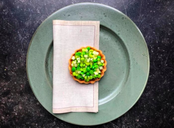 An overhead view features a delicate pastry adorned with chopped greens.