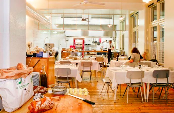 A vibrant dining area featuring a prep station in the foreground, with patrons seated at tables in the background.