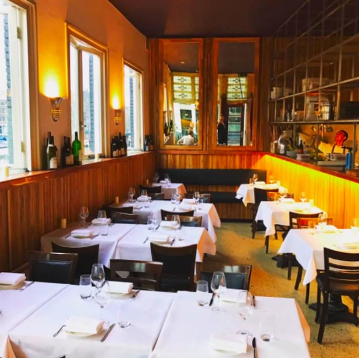 A dining area adorned with wooden paneling and tables elegantly set with white tablecloths.