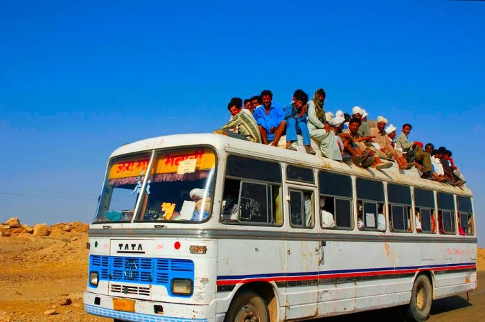 A bus packed with people as it navigates through a dry landscape