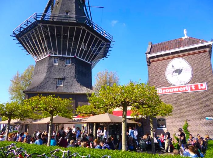 Patrons enjoying drinks on an outdoor terrace beneath a large windmill.