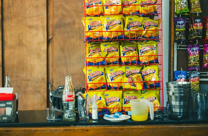 A preparation area stocked with bags of Picaritas chips alongside cooking tools and various food and drink items.