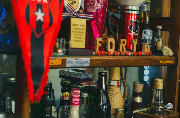 Rows of liquor bottles, sports memorabilia, and various trinkets.