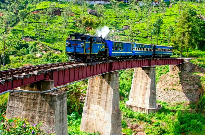 A charming blue heritage train traverses a bridge on the Nilgiri Mountain Railway (NMR) en route to Ooty (Udagamandalam).