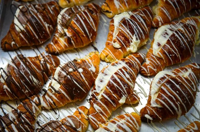 A tray of cornetti adorned with drizzles of dark and white chocolate.