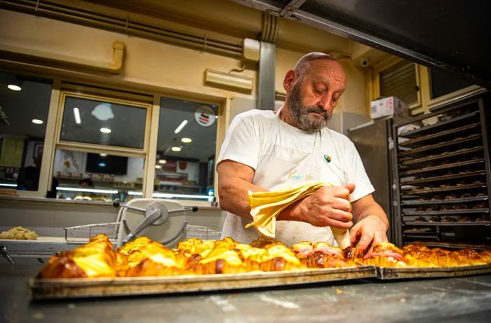 A pastry chef fills cornetti with creamy goodness.