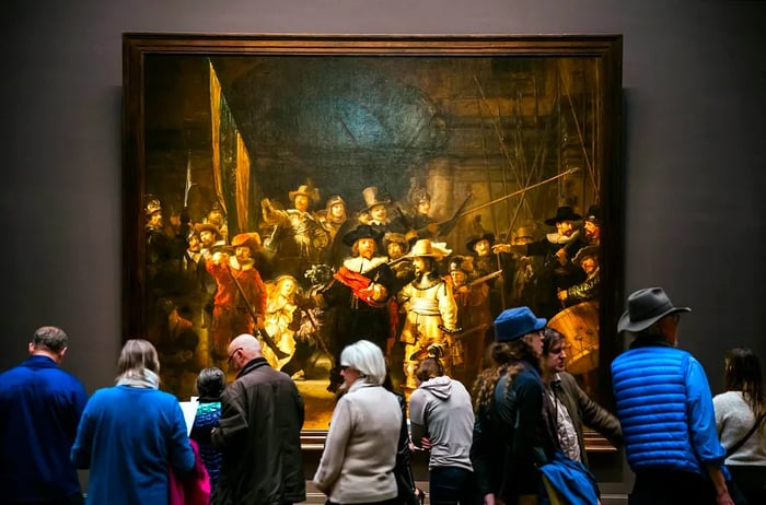 A massive 17th-century artwork displayed on the wall, with a crowd gathered to admire it