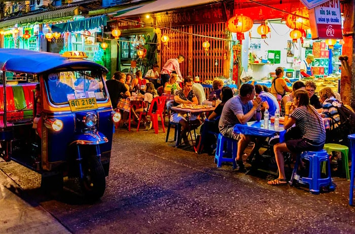 Diners enjoy meals at outdoor tables, savoring street food delicacies.