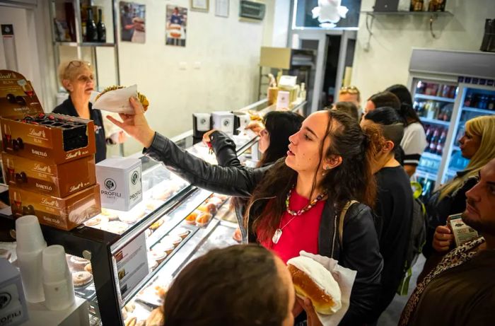 A customer stretches to grab a pastry from the display case.