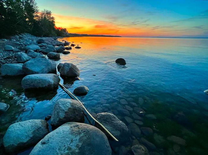 The sky glows orange over a lake as the sun sets