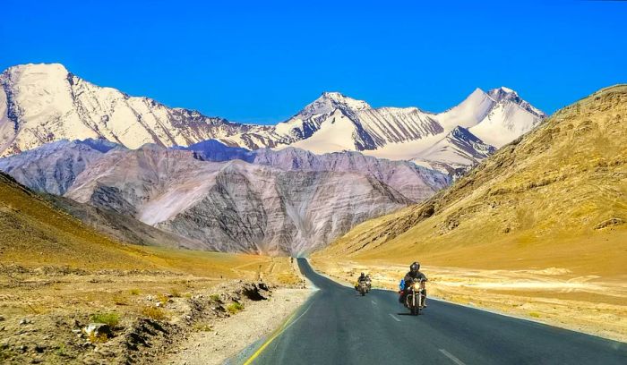 Motorcyclists navigate the scenic mountain landscape in Ladakh, India.