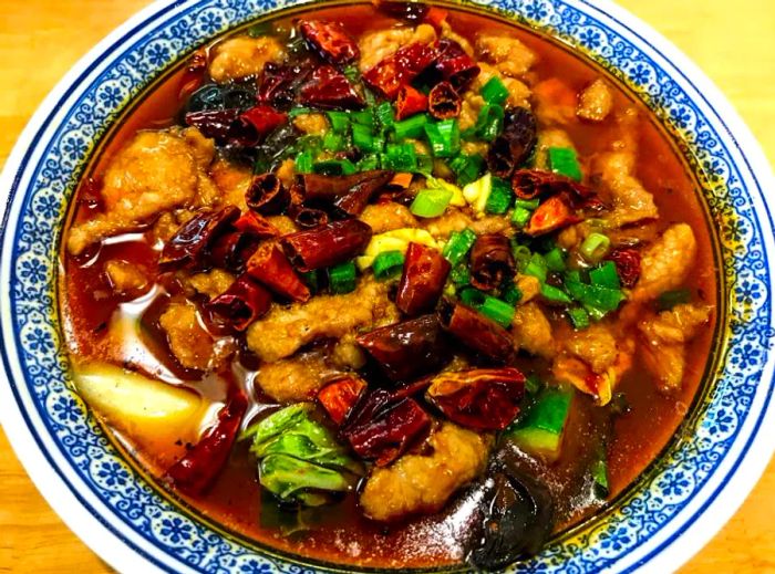 A beautifully presented bowl of beef and vegetables in sauce, adorned with a decorative rim.