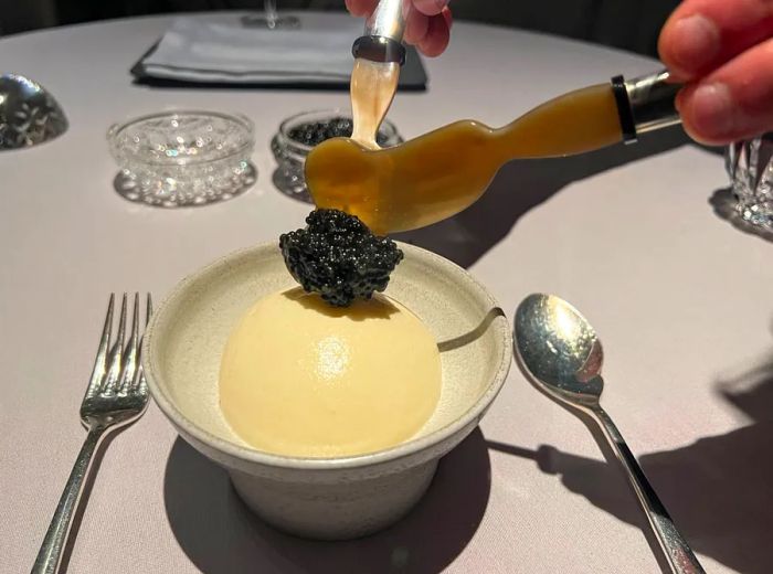 A server adds caviar atop a dome of egg cream.