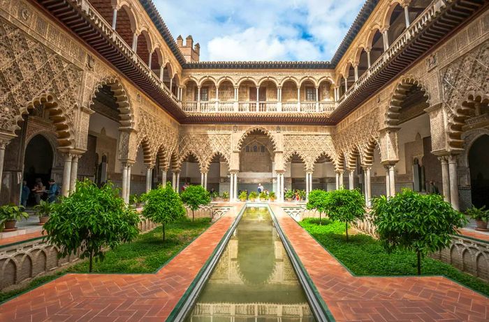 A courtyard featuring an ornate building and a small rectangular pond.