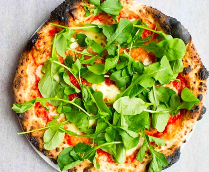 From above, a whole pizza topped with spinach