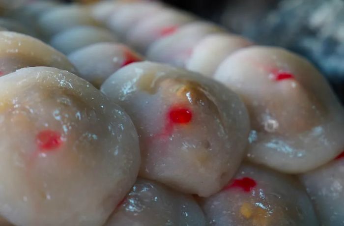 A close-up of meatballs adorned with vibrant red dots.