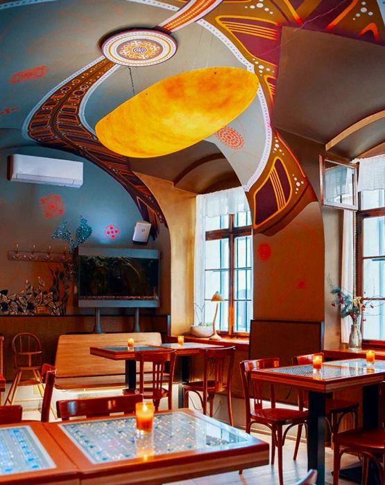 A dining area adorned with flowing designs and a striking orange, egg-shaped pendant light.