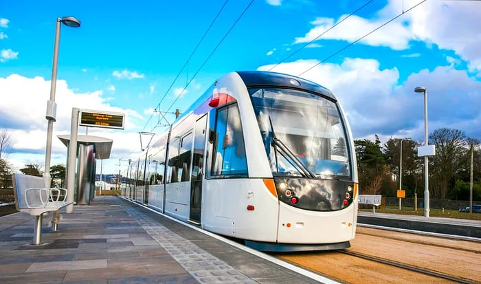 A sleek white tram stands at a platform at a tram stop