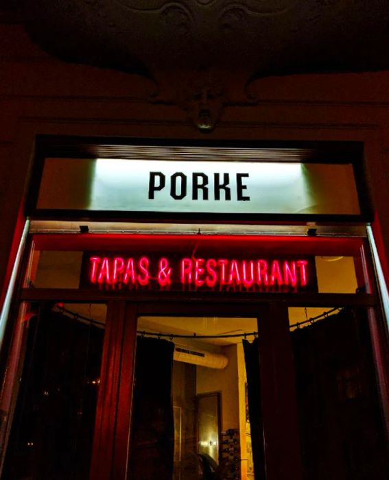 Illuminated signage for the Porke restaurant glows in the darkness, featuring a neon sign that reads Tapas & Restaurant.