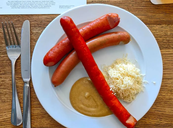 A serving of three sausages accompanied by a mound of sauerkraut and a dollop of mustard.