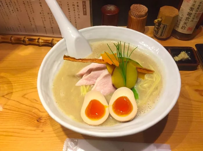 A bowl of ramen adorned with a boiled egg, sliced meat, and various toppings.