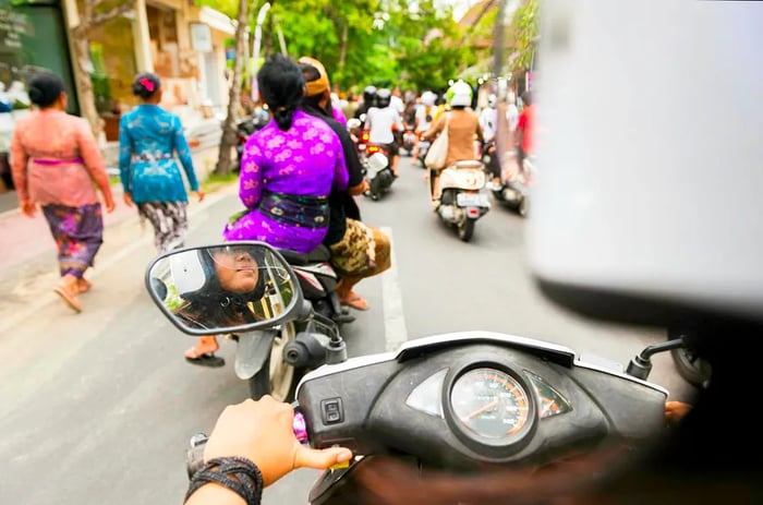 A group of motorcycle riders navigating a narrow urban street