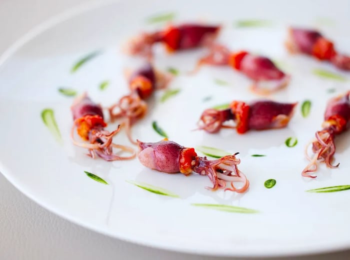 A plate featuring tiny firefly squids accompanied by a vibrant green sauce.