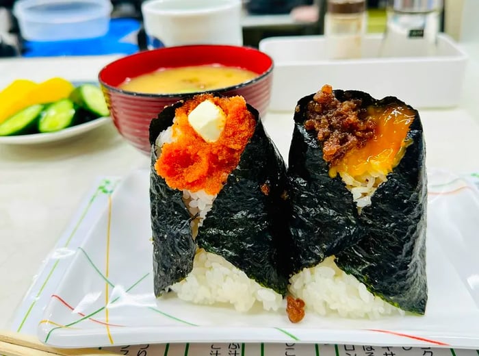 Two onigiri upright on a plate, showcasing vibrant fillings at the tops.