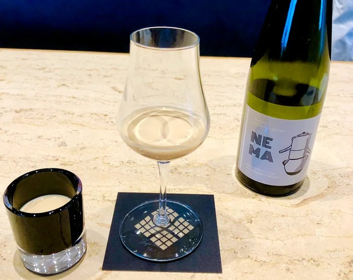 A wine glass and a lowball glass featuring coffee drinks, with a bottle displayed on a marble counter.