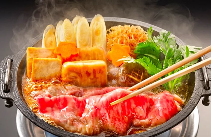 A vibrant bowl of shabushabu, with chopsticks lifting tender slices of meat from the flavorful broth.