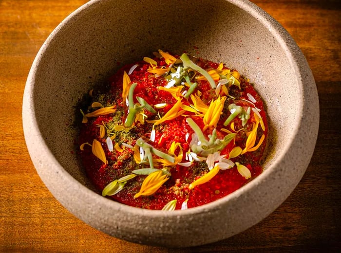 A visually stunning dish resembling a vibrant forest floor, adorned with roe, flowers, and micro-vegetables.