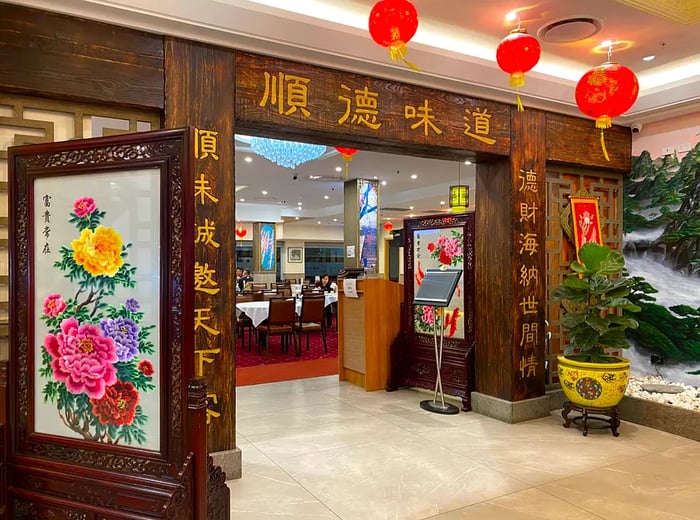 A restaurant entrance adorned with floral illustrations and Chinese characters, revealing a dining room in the background.