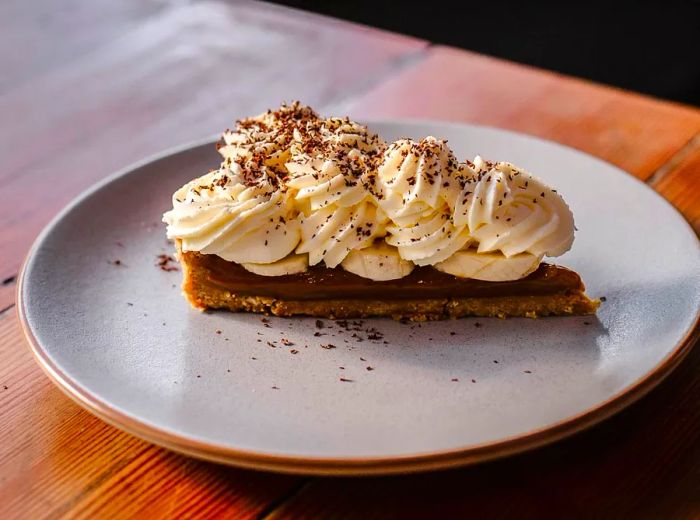 A slice of pie adorned with generous swirls of whipped cream.