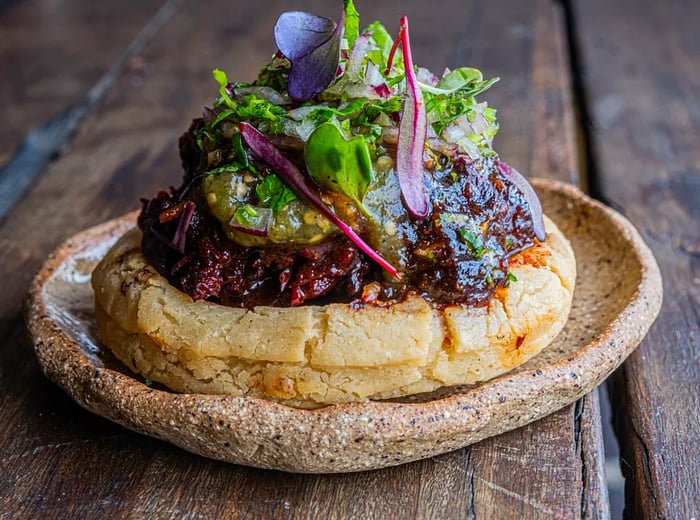 A sope adorned with a generous scoop of hibiscus jam and fresh greens.