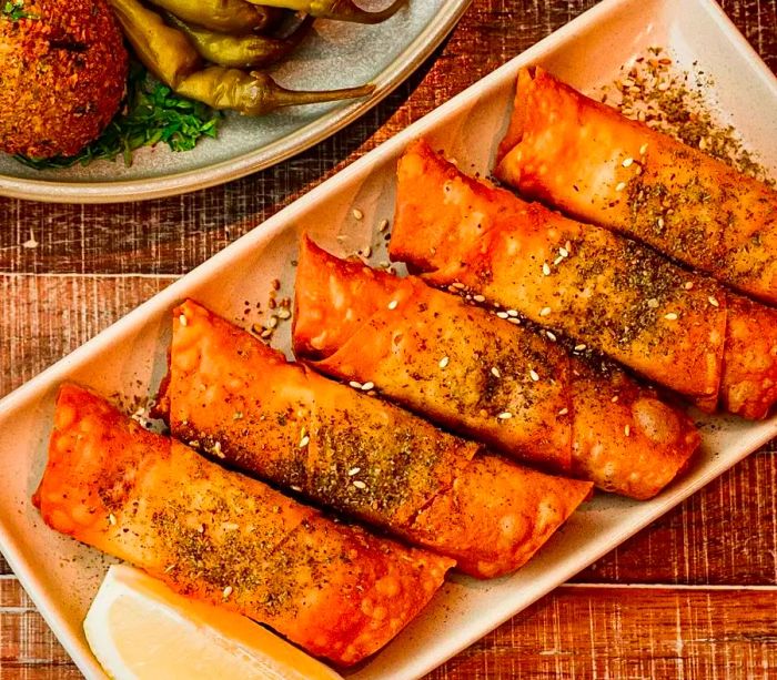 Spring rolls served on a platter alongside a lemon wedge.