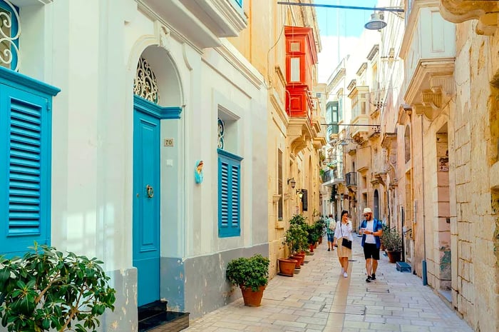 Tourists strolling through the narrow streets lined with wooden doors and historic homes in Vittoriosa.