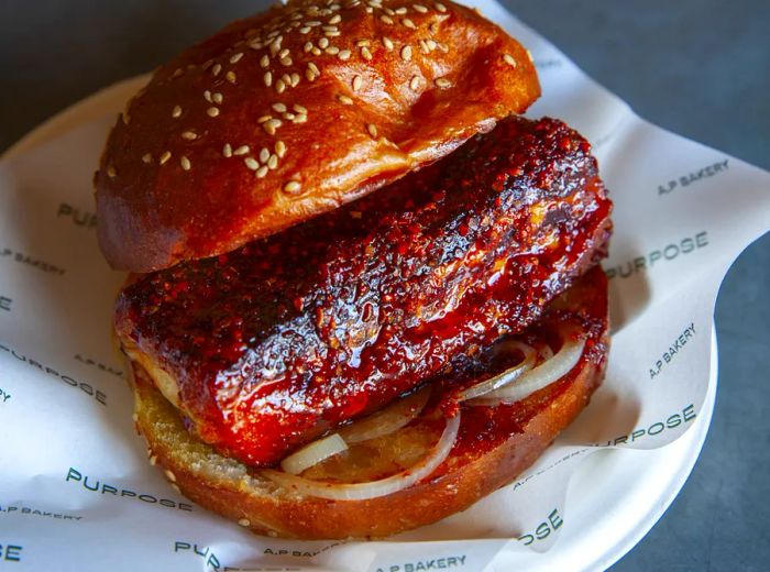 A chunk of warm, red cheese drizzled with hot honey nestled in a sesame seed bun.