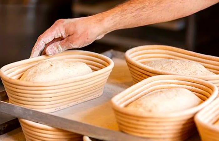 A baker meticulously arranging dough in rising baskets.