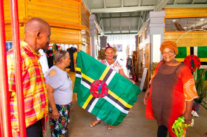 A woman proudly displays a Dominican flag alongside other visitors and vendors at the Old Market in Roseau, Dominica.