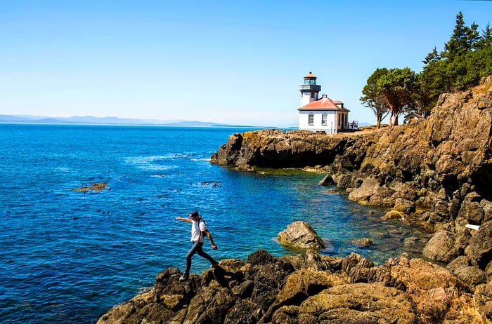 A person navigating the rocky terrain near the lighthouse on San Juan Island, Washington, USA