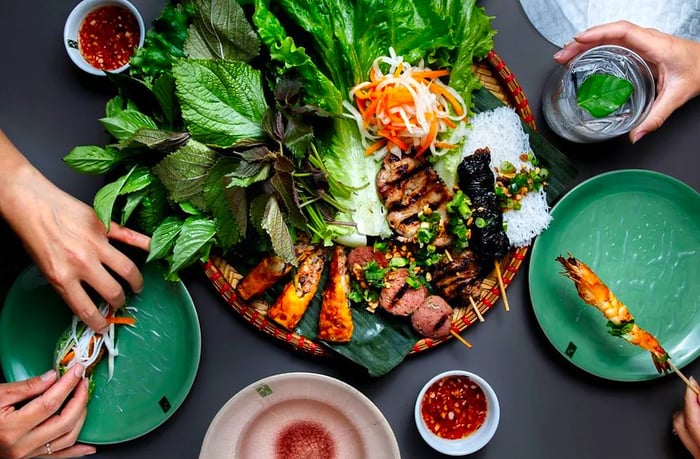 Diners reach into a heaping tray filled with an array of vegetables, skewers, and fried delights from above.