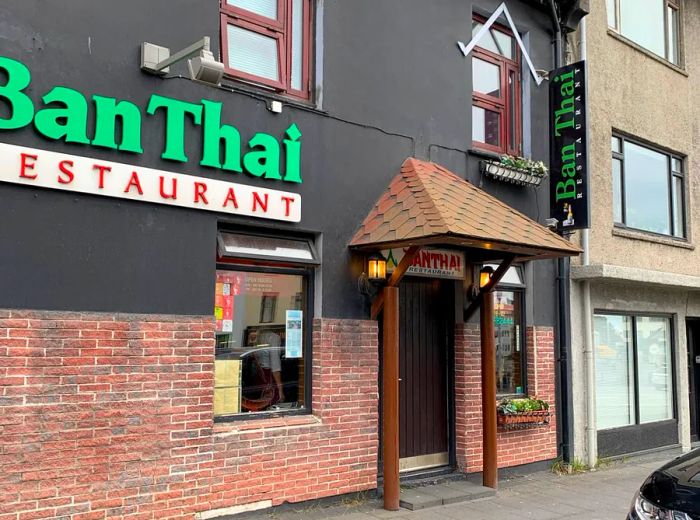 The exterior of a compact two-story building features straightforward signage for Ban Thai, an awning above the entrance, and small lanterns flanking the door.